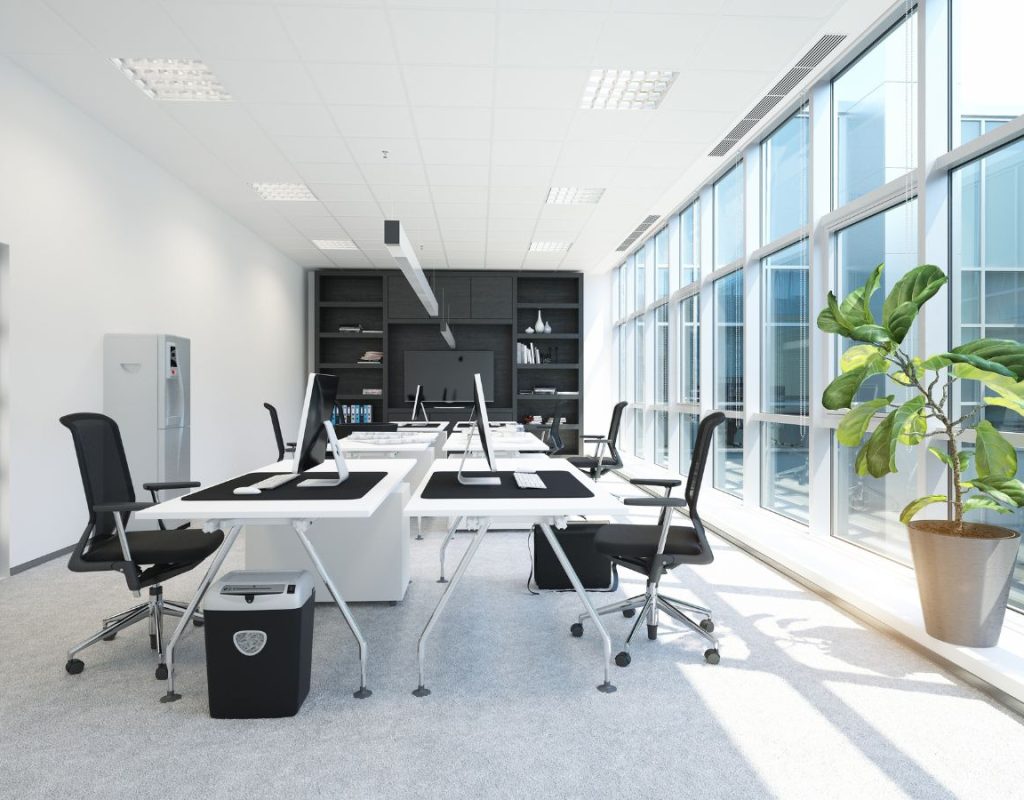 Professional cleaning technician using HEPA vacuum and sanitizing high-touch surfaces in modern Apex, NC workspace