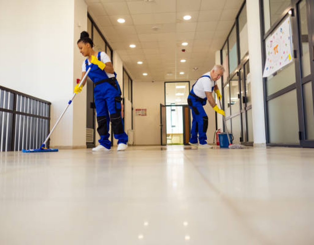 Cleaner preparing office lobby and glass entry before employees arrive